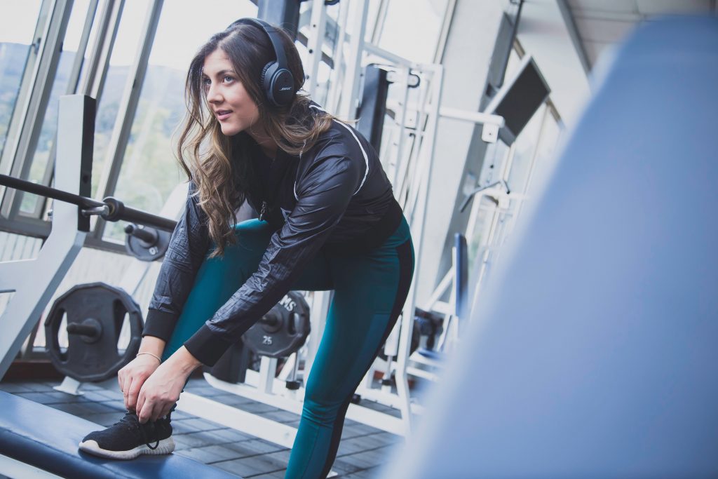 A lady in the gym using headphones. Fitness industry needs more knowledge on music.